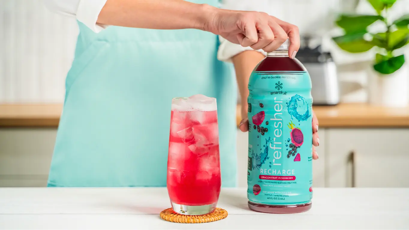 Bottle of Smartfruit Refresher being held next to a glass of prepared Refresher