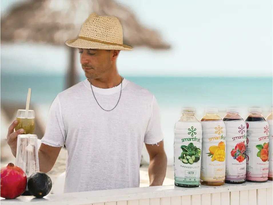 Bartender holding a glass of Smartfruit with bottles shown on a ledge