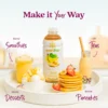 A Smartfruit Sunny Banana purée mix bottle displayed on a white tray surrounded by banana-based foods and drinks including smoothies, milk tea, pancakes with syrup, and ice cream dessert. Text highlights different uses: smoothies, teas, desserts, and pancakes.