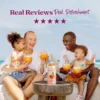 A smiling family sitting outdoors near the ocean enjoys tropical smoothies together while a bottle of Smartfruit Tropical Harmony purée mix sits on a table in front of them. Text above reads “Real Reviews, Real Refreshment” with five stars.