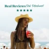 A woman wearing a straw hat stands at the beach while drinking a bright pink refresher beverage through a straw. Text above reads “Real Reviews, Real Refreshment” with five stars.