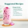 A creamy pink dragon fruit drink served in a tall glass with ice and dragon fruit pieces. Text shows a suggested recipe called Dragon Drink made with Smartfruit Recharge Refresher, vanilla plant-based milk, water, crushed ice, and freeze-dried dragon fruit.
