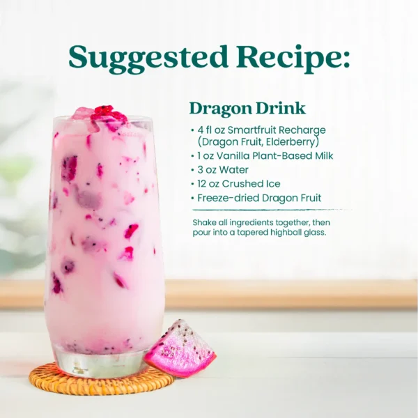 A creamy pink dragon fruit drink served in a tall glass with ice and dragon fruit pieces. Text shows a suggested recipe called Dragon Drink made with Smartfruit Recharge Refresher, vanilla plant-based milk, water, crushed ice, and freeze-dried dragon fruit.