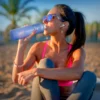 Woman on a beach drinking from the Smartfruit Rincon Bottle