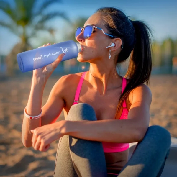 Woman on a beach drinking from the Smartfruit Rincon Bottle