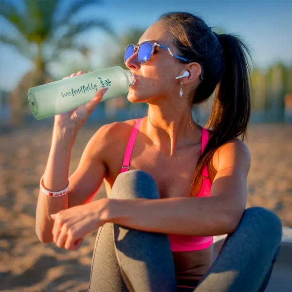 Woman on a beach drinking from the Smartfruit Rincon Bottle